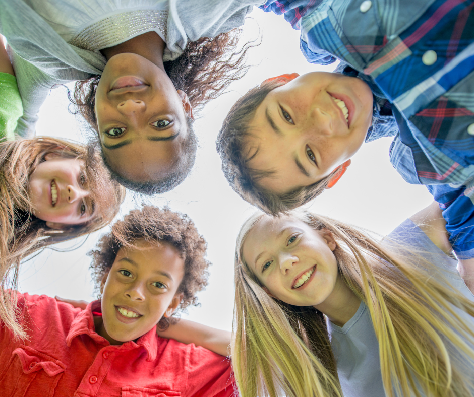 Five Adolescents Standing Together in a Circle and Looking Down Smiling at Camera