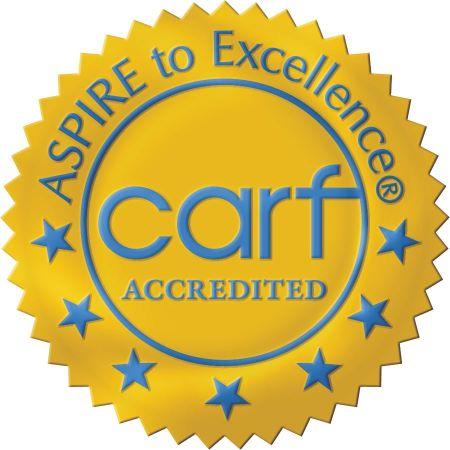 Gold Seal with light blue text that reas Aspire to excellence carf accredited . Seven blue stars at the bottom of the seal